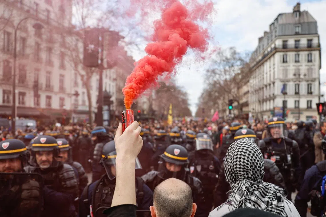 A protester lighting a flare during clashes with police at a protest against racism and the rise of the far right, in Paris, on March 22.