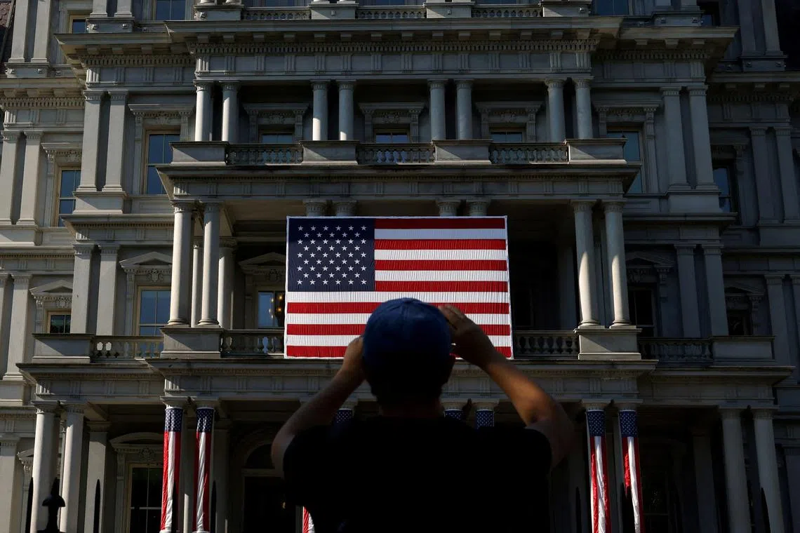 FILE PHOTO: A tourist photographs a U.S. flag on the Eisenhower Executive Office Building, in Washington, U.S., July 4, 2023. REUTERS/Julia Nikhinson