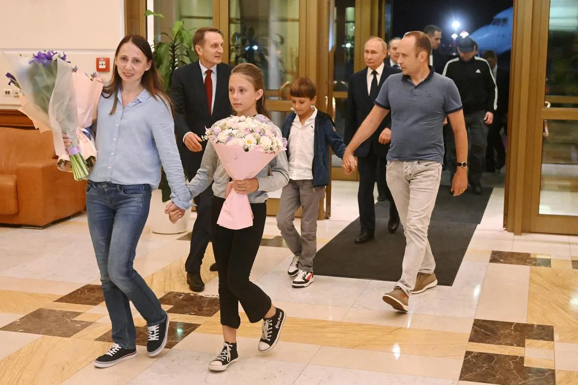 Russian President Vladimir Putin walks behind Russian nationals Artyom Dultsev, Anna Dultseva and their children following a prisoner exchange between Russia with Western countries.