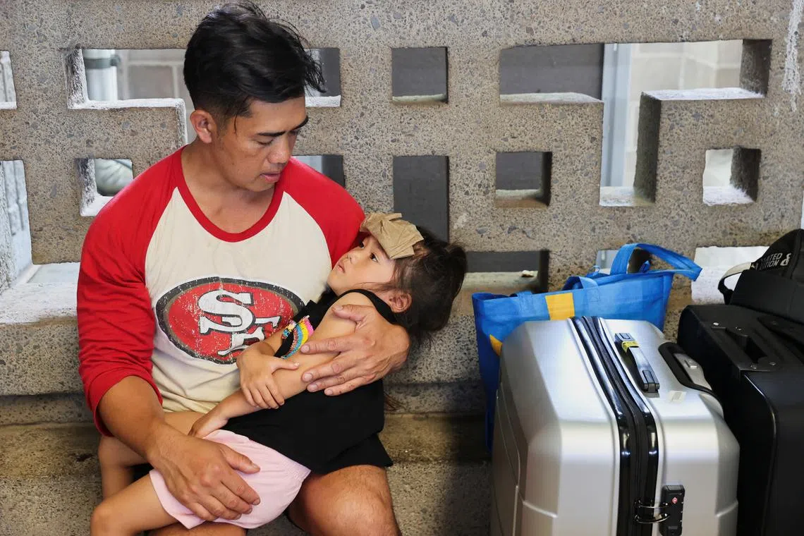 Vixay Phonxaylinkham, holding his child Lana, 4, as she overheats, while waiting for their flight to California at Kahului Airport, Aug 10. Phonoxaylinkham, his wife, and their five children were caught in the Lahaina wildfires and survived by exiting their car and spending four hours in the ocean as the west Maui wildfires raged around them. 