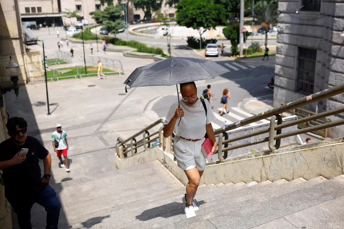 A woman protects herself from the sun with an umbrella during a heatwave in the centre of Sao Paulo, Brazil March 15, 2024. REUTERS/Amanda Perobelli/ File Photo