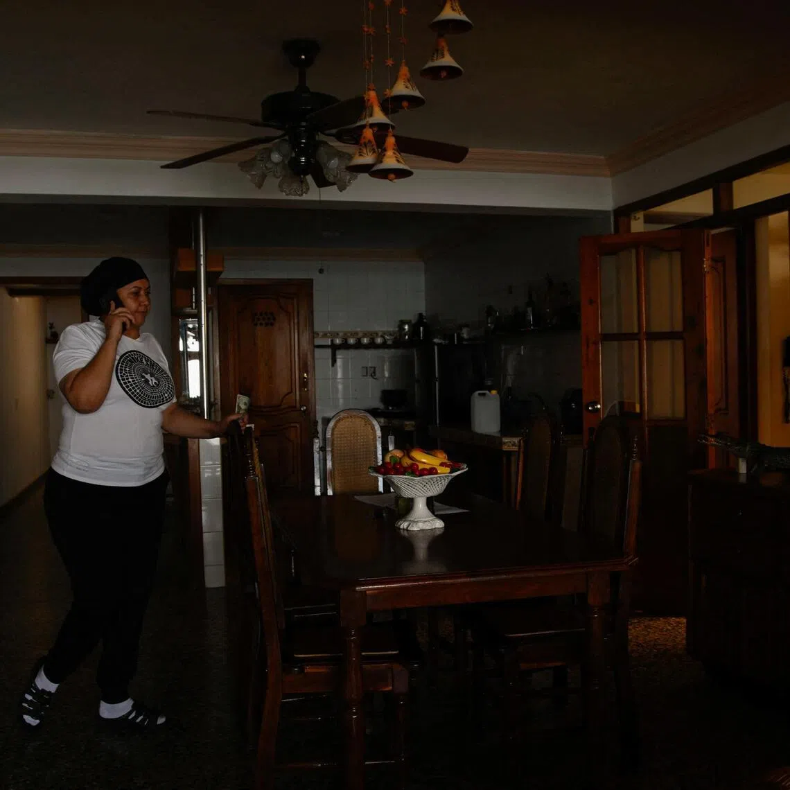 A resident of Cuba talks on the phone during a power cut on April 8, 2026, saving her energy backup system for when it is needed.
