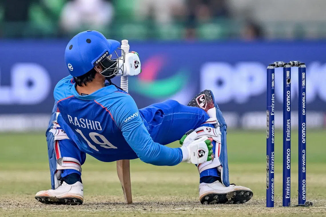 Afghanistan's Rashid Khan falls after playing a shot in the ICC Champions Trophy one-day international (ODI) match against Australia at the Gaddafi Stadium in Lahore on Feb 28, 2025.