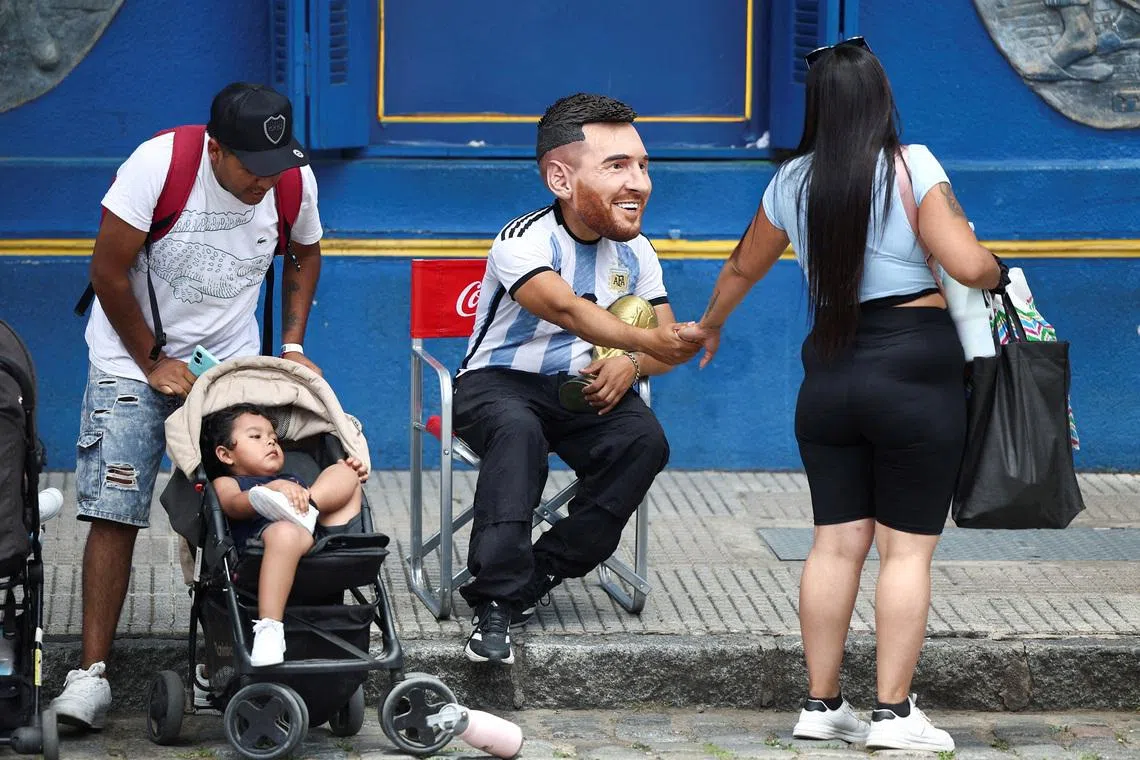 FILE PHOTO: A man wearing a mask depicting Argentine soccer star Lionel Messi, greets a woman as he holds a replica of the FIFA World Cup trophy, ahead the FIFA World Cup draw, in Caminito, Buenos Aires, Argentina December 5, 2025. REUTERS/Agustin Marcarian/File Photo