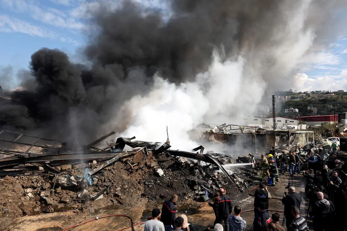 Firefighters working as smoke billows at a site that was hit by an airstrike on Lebanon's coast around 60 km north of the border with Israel, during a media tour, Lebanon Feb 20, 2024. 