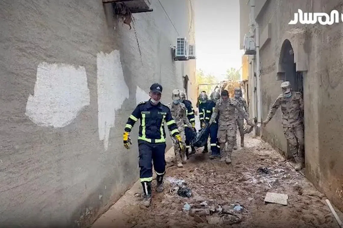 Rescue workers carry a dead body amidst rescue operations in the aftermath of the floods in Derna, Libya September 13, 2023 in this screen grab obtained from a video. AL-Masar TV/Handout via REUTERS.  THIS IMAGE HAS BEEN SUPPLIED BY A THIRD PARTY. DO NOT OBSCURE LOGO. LIBYA OUT. NO COMMERCIAL OR EDITORIAL SALES IN LIBYA