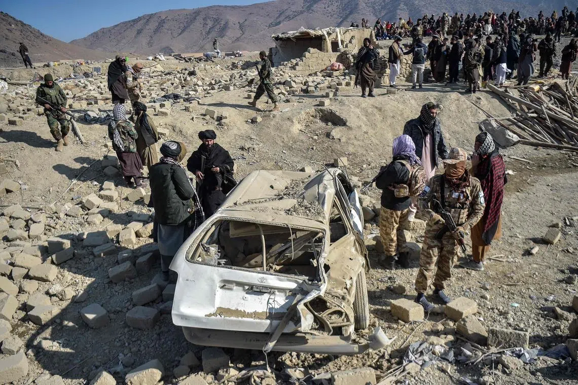Taliban security personnel inspect a damaged car two days after air strikes by Pakistan in the Barmal district of eastern Paktika province, on Dec 26.