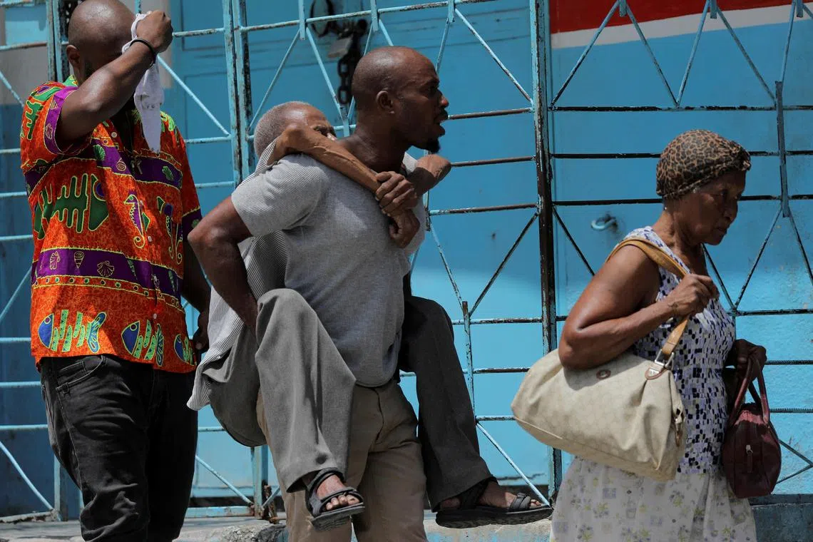 A Port-au-Prince resident carries an elderly man as they flee their Carrefour Feuilles neighbourhood , amid a gang takeover.