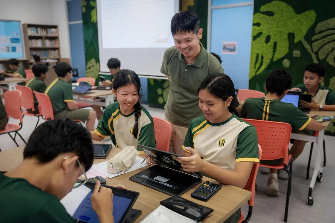 Tampines Secondary School mathematics teacher Charles Yip guiding Secondary Two students (clockwise from bottom left) Alexis Koh, Reiko Toh and Raina Mahani as they use AI-powered learning tools.