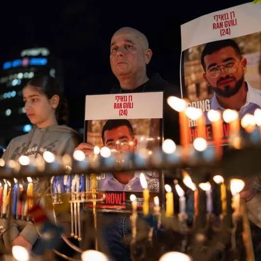  Israelis holding placards bearing the face of Ran Gvili in Tel Aviv on Dec 21, 2025, calling for the return of his remains.