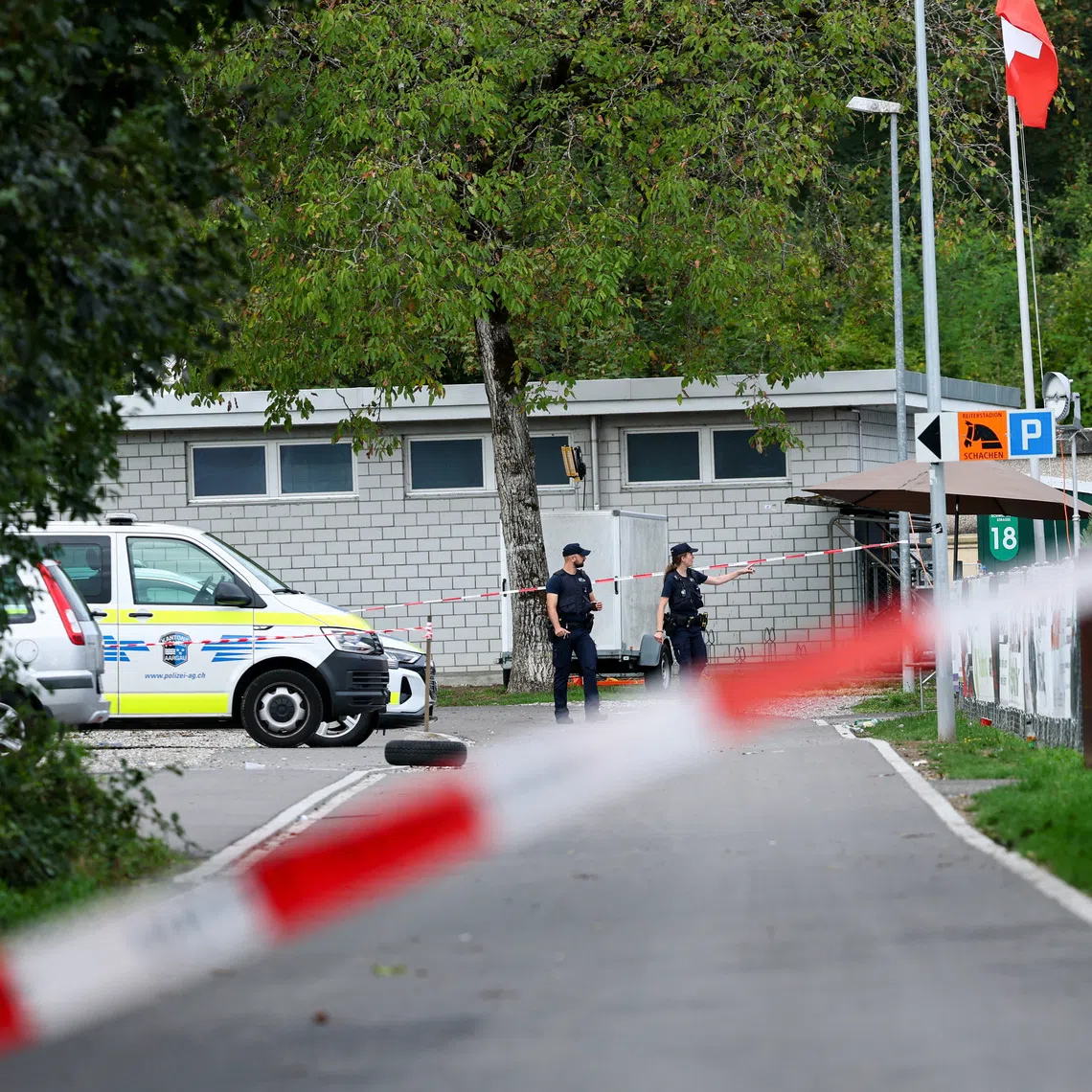 Police officers walk near the site of a rave party, following a deadly shooting incident at an event on Sunday, near the Schachen horse racing track, in Aarau, Switzerland, on Aug 31.