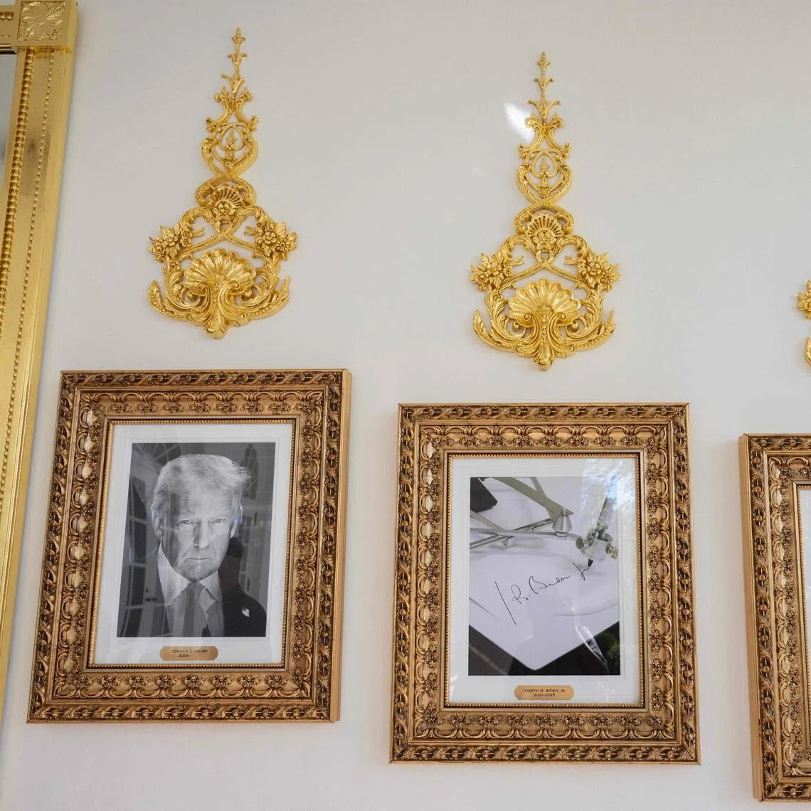 Framed portraits of US President Donald Trump flank a image of former US President Joe Biden's signature and an autopen along "The Presidential Walk of Fame" outside the Oval Office.