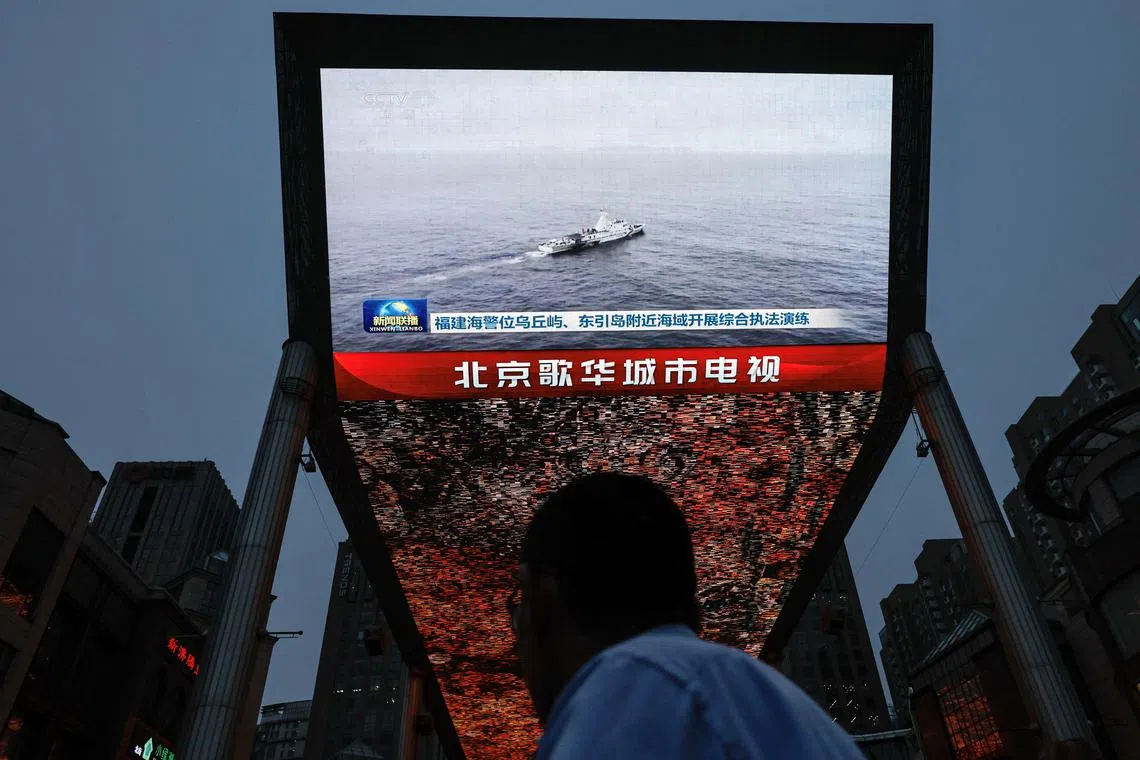 A person looks at a screen showing news footage of military drills conducted in areas around the island of Taiwan by the Eastern Theatre Command of the Chinese People's Liberation Army (PLA), in Beijing, China May 23, 2024. REUTERS/Tingshu Wang