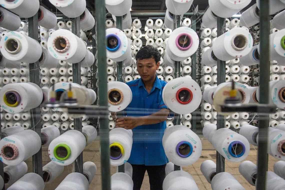 A worker arranging rolls of thread for a weaving loom at a textile factory in West Java, Indonesia. 