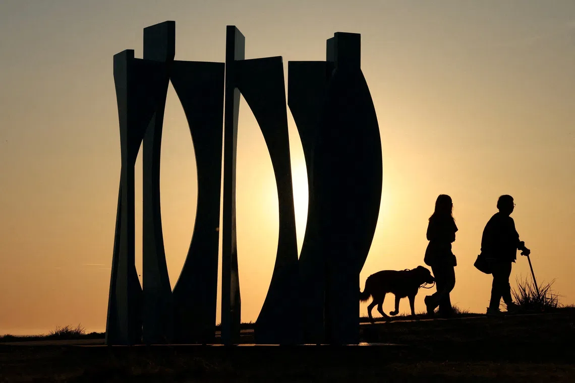 People walking past a sculpture titled ‘Cyan Forest’ by artist Philip Spelman, on the opening day of the 'Sculpture by the Sea' outdoor exhibition in Bondi, Australia, Oct 17, 2025. 