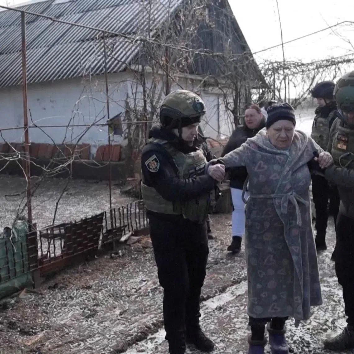 Ukrainian national police officers assist a woman during an evacuation of residents from the Tavriiske and Yurkivka villages in Ukraine's Zaporizhzhia region, amid Russia's attack on Ukraine, in this screengrab from a video, February 3, 2026. Reuters TV via REUTERS