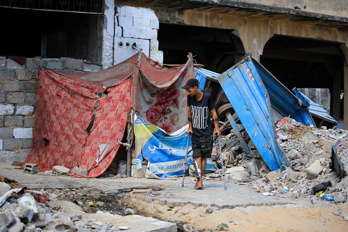 An injured Palestinian man walks on crutches near a tent that houses residents who lost their homes in the city of Khan Yunis.