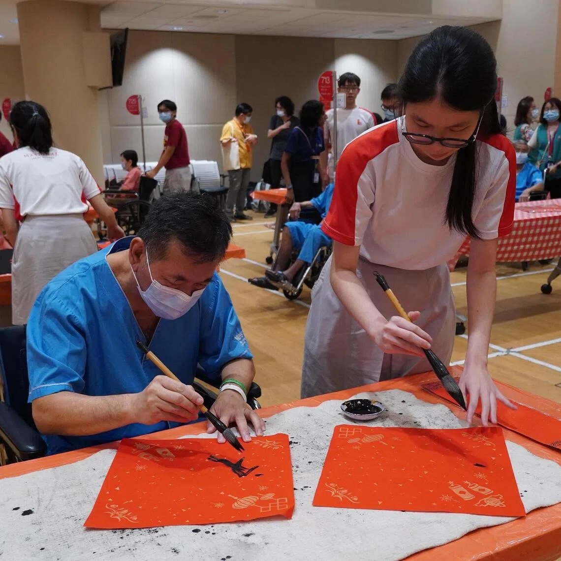 National Junior College student volunteers doing calligraphy with seniors at the Harmony of Horses Chinese New Year Concert.