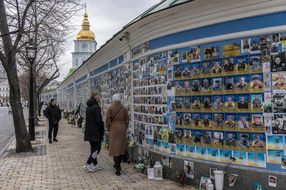 People view photos of fallen Ukrainian soldiers on a wall outside St. Michael's Golden-Domed Monastery in Kyiv, on Feb 24.