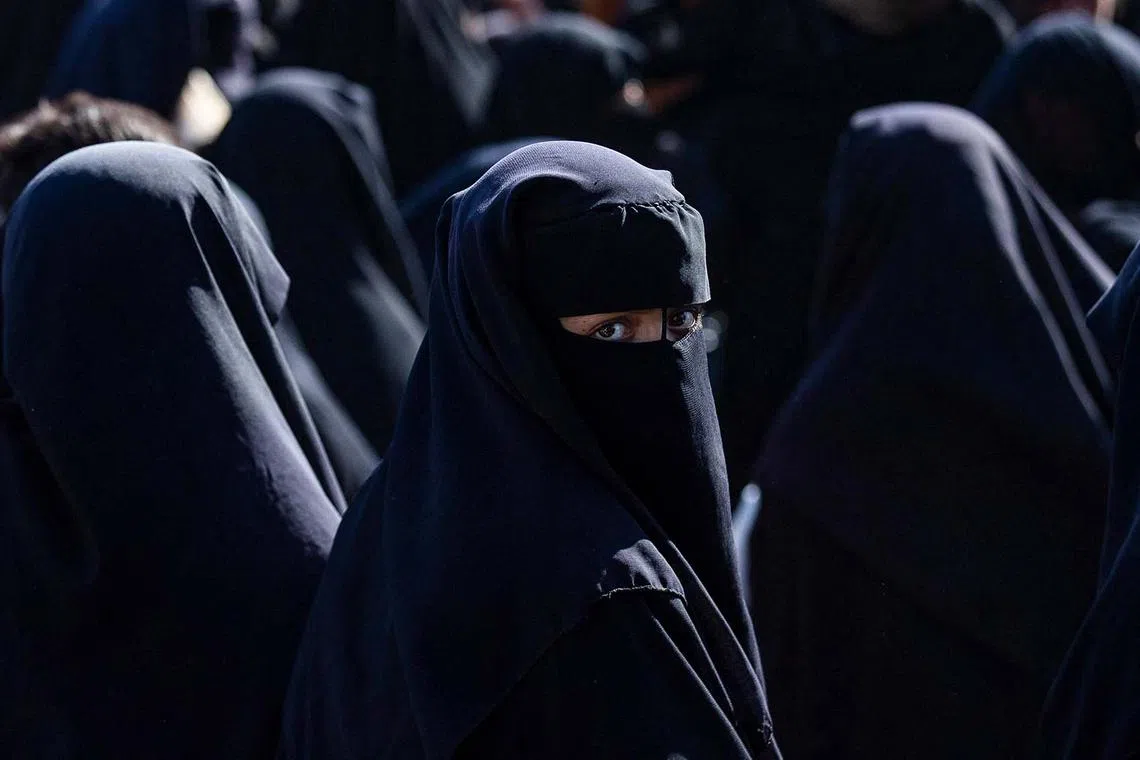 A woman looking on as Iraqi nationals prepare to leave the Kurdish-run al-Hol camp in Syria ahead of their return to Iraq on Aug 28, 2025. 