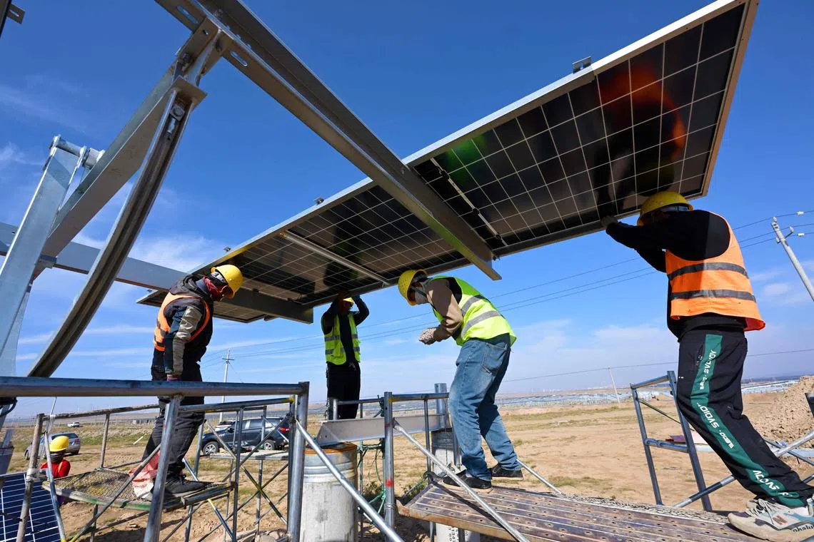 Workers install solar panels at the Shagehuang photovoltaic base in Lingwu, in China’s northern Ningxia region on Oct 28, 2024.