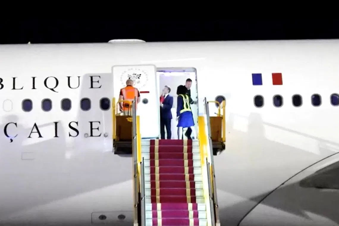 French President Emmanuel Macron stands near the door of a plane, as a hand appears and pushes his face away, in Hanoi, Vietnam on May 25.