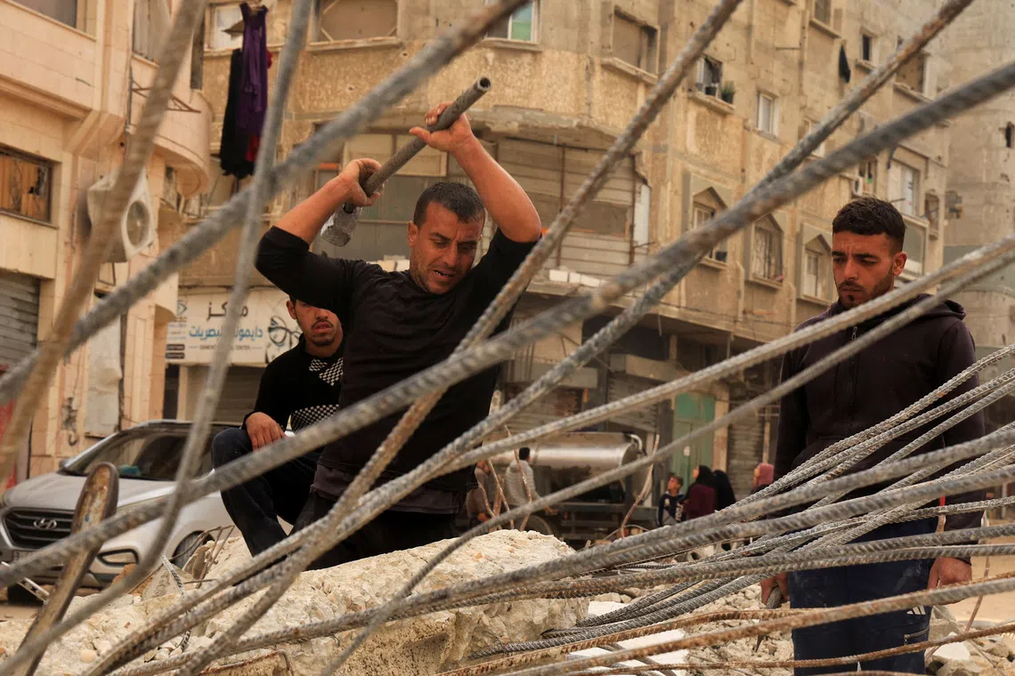 Palestinian workers break concrete to extract steel bars from destroyed homes, relying only on simple hand tools amid a severe shortage of construction materials caused by long-standing restrictions on the entry of cement and iron, in Khan Younis in the southern Gaza Strip, December 9, 2025. REUTERS/Haseeb Alwazeer