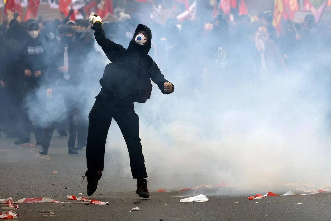 A masked protester throwing an object, amid clashes with French police in Paris on Oct 6.