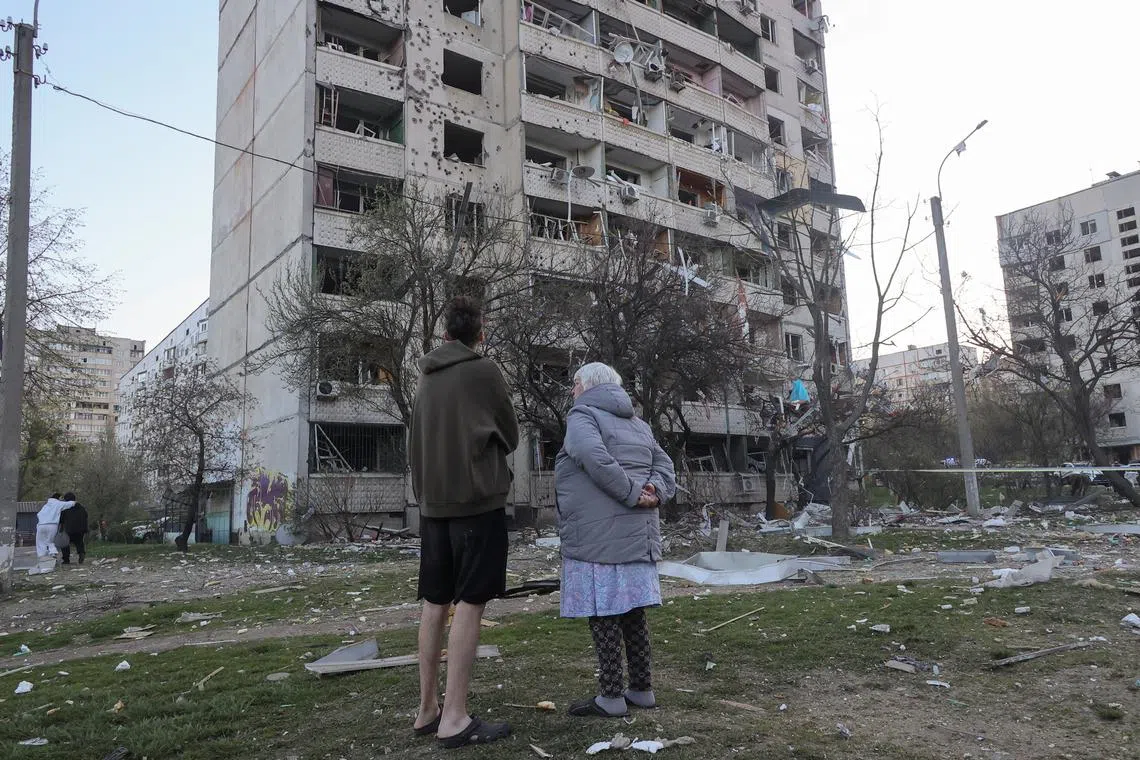 Residents stand in front of an apartment building damaged by a Russian missile strike, amid Russia's attack on Ukraine, in Kharkiv, Ukraine April 18, 2025. REUTERS/Vyacheslav Madiyevskyy