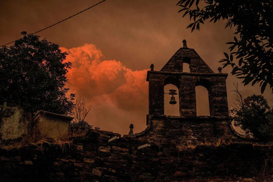 A pyrocumulus cloud forms as smoke rises from a wildfire as seen from a cemetery in the village of Vilarmel, Lugo area, Galicia region, Spain, August 16, 2025. REUTERS/Mikel Konate