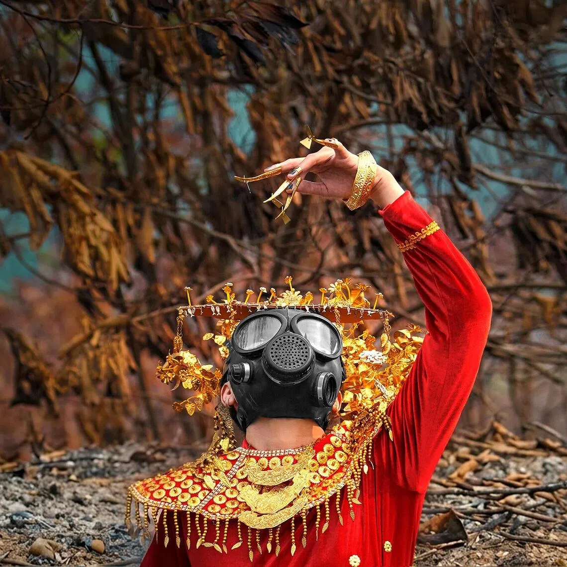 A woman in traditional South Sumatran wedding clothes dancing in a burnt out forest near Palembang, Indonesia, as part of a performance art piece by art collective Jaga Api.