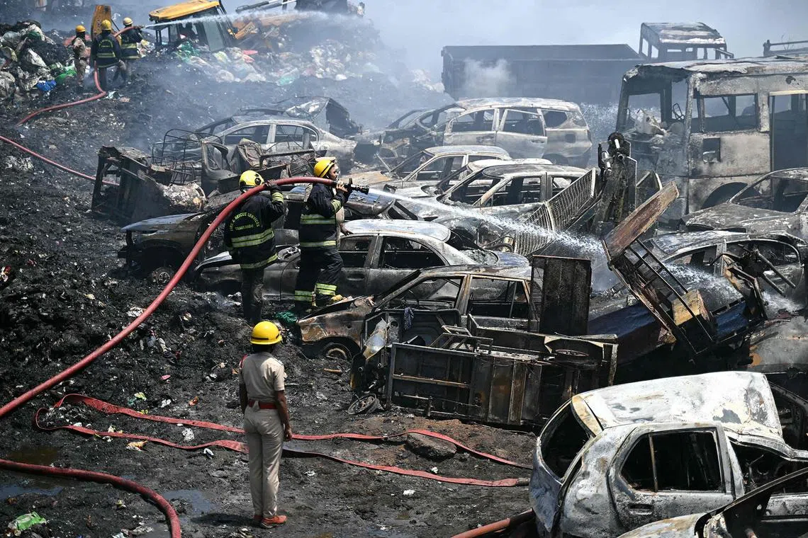 Firefighters dousing flames among charred, abandoned vehicles following a fire at a debris segregation area in Chennai, India, on June 4, 2026. 