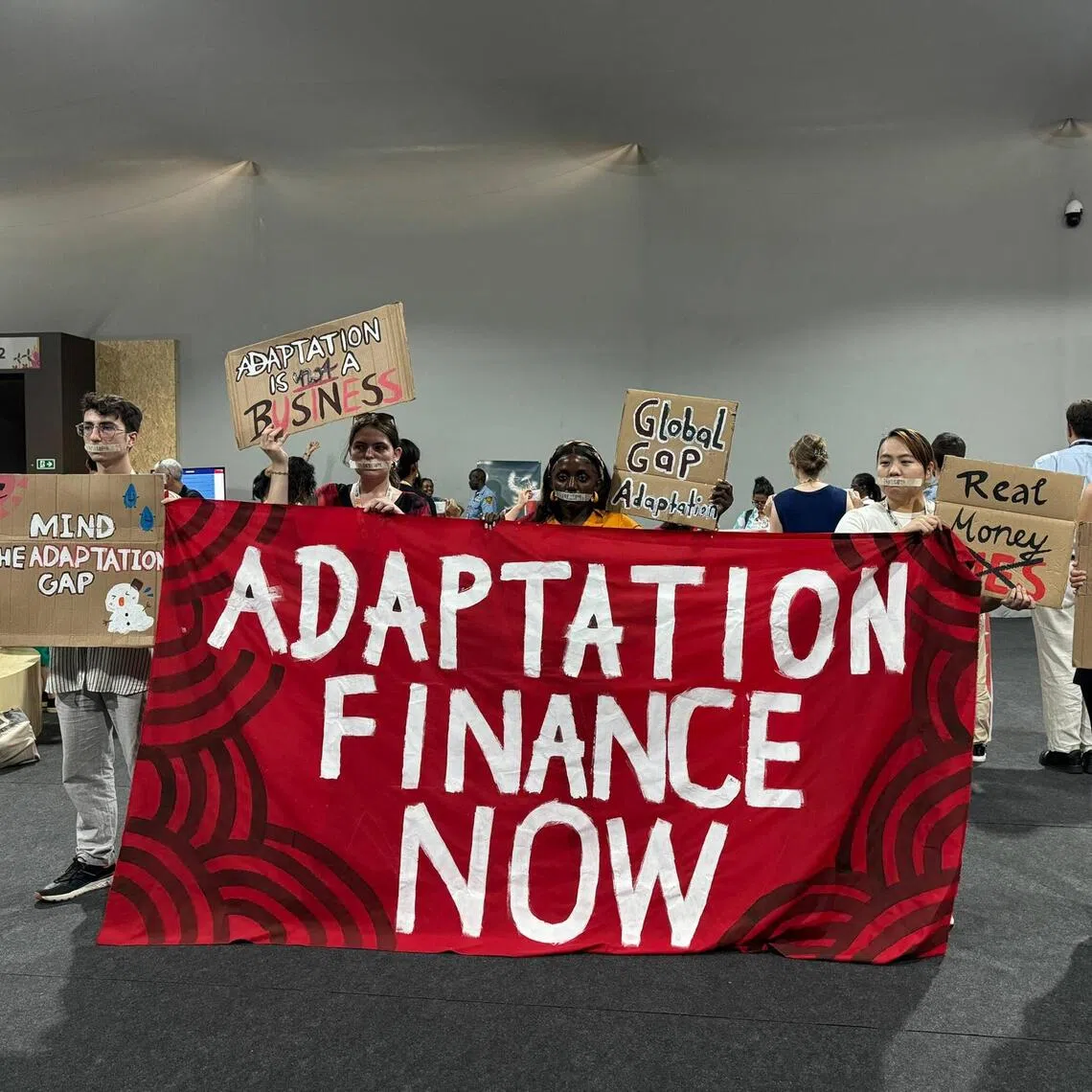 Adaptation Finance Now! protestors onducting a silent demonstration outside a press conference room inside the COP30 Blue Zone.