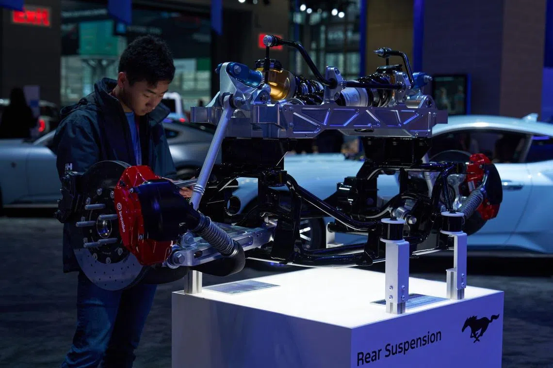 An attendee examines the rear suspension of a Ford Mustang sports car during the 2024 New York International Auto Show (NYIAS) in New York, US, on Thursday, March 28, 2024. The event, which first opened in November 1900, is North America's oldest and largest attended auto show. Photographer: Bing Guan/Bloomberg