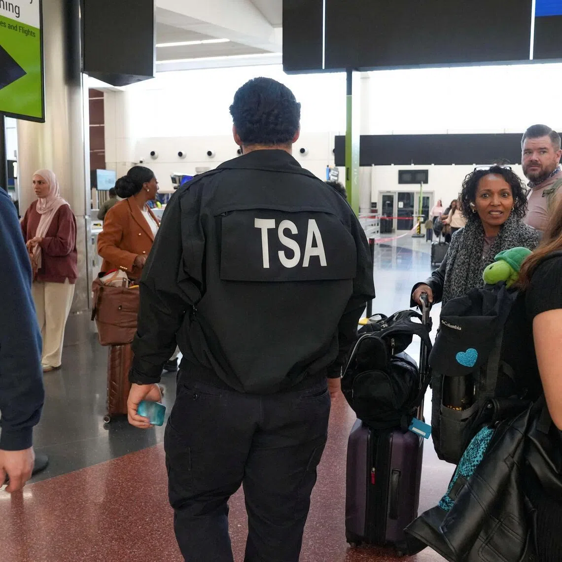 A TSA agent walking past passengers waiting in long lines at Hartsfield-Jackson Atlanta International Airport in Atlanta, Georgia, on March 20, amid a partial government shutdown.