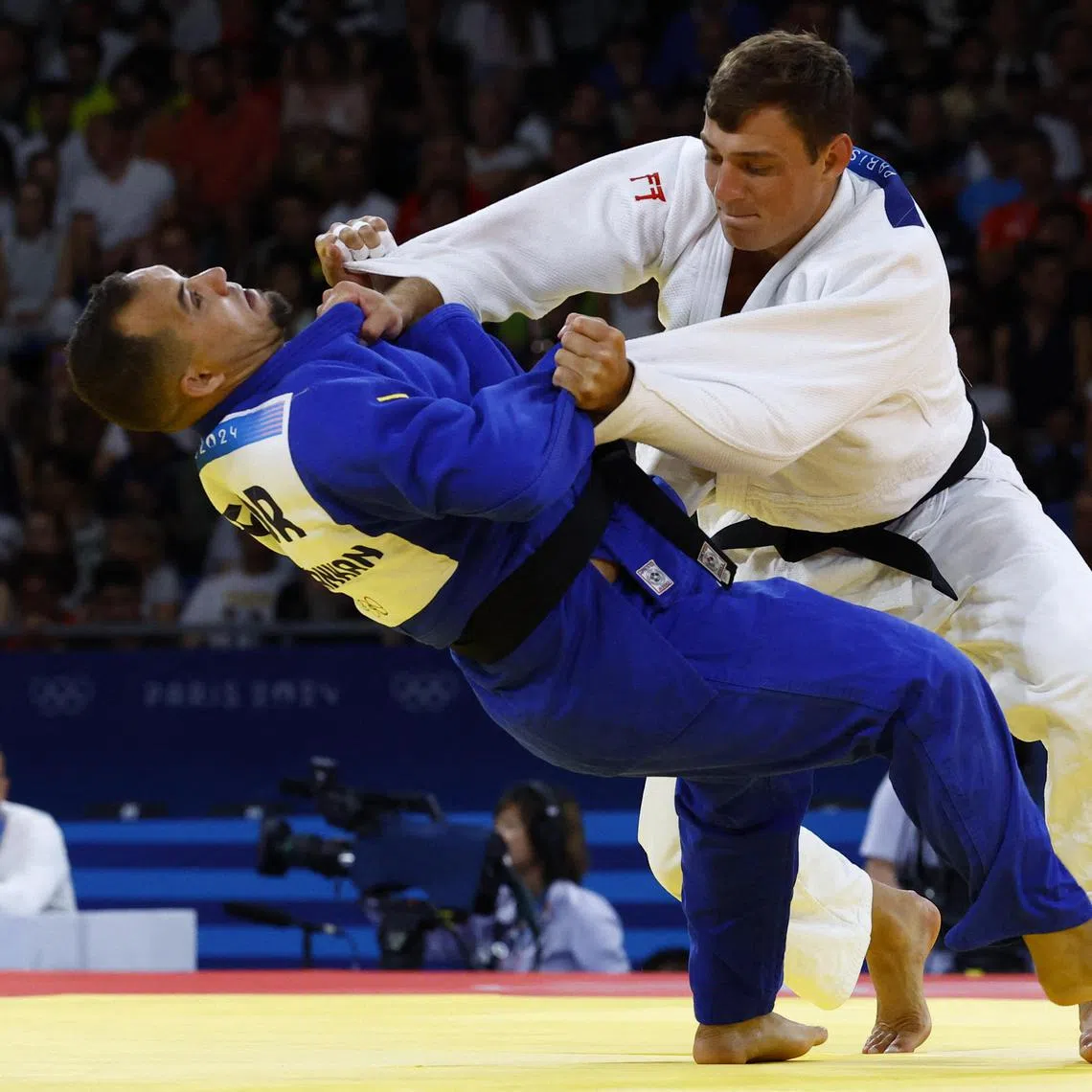 Judoka Adnan Khankan (blue) of the Refugee Olympic Team grapples with  Daniel Eich of Switzerland.