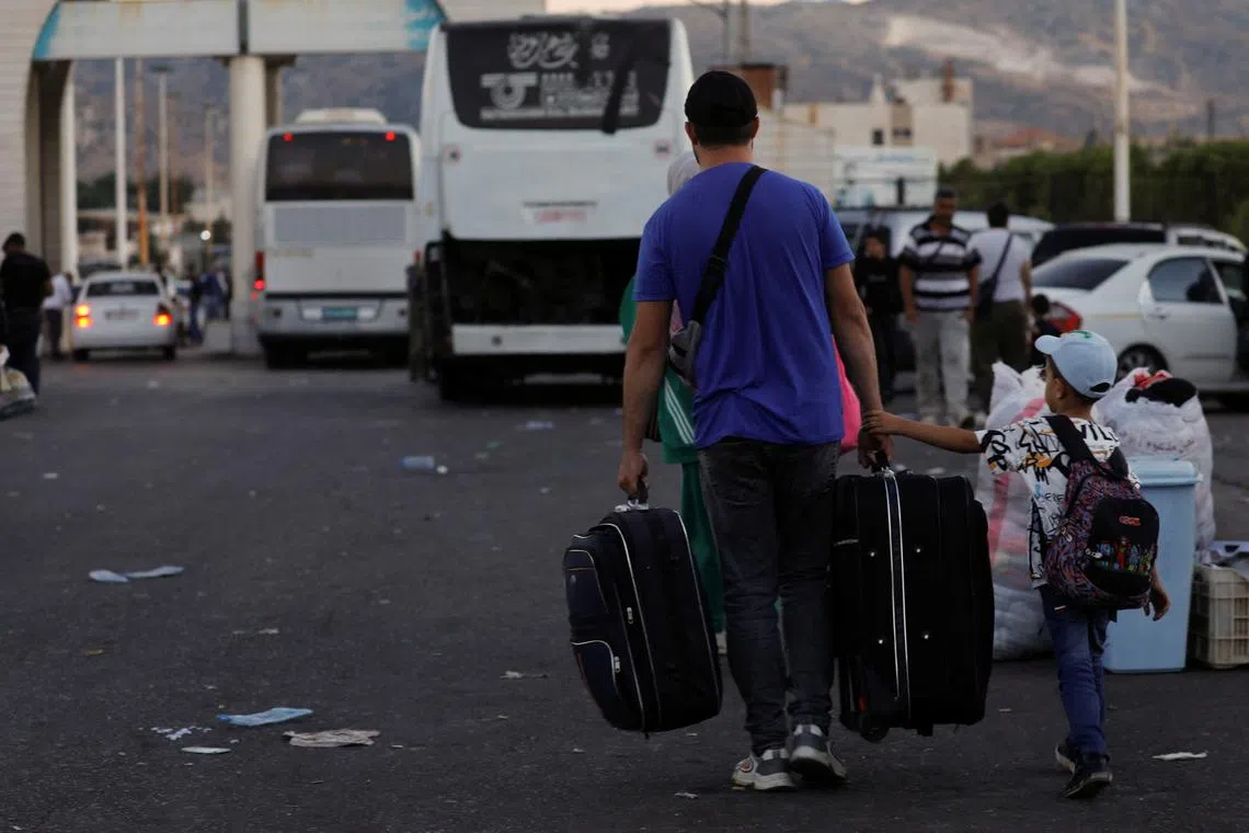 FILE PHOTO: Syrians, who were living in Lebanon and returned to Syria due to ongoing hostilities between Hezbollah and Israeli forces, carry belongings at the Syrian-Lebanese border, in Jdaydet Yabous, Syria, September 25, 2024. REUTERS/Yamam al Shaar/File Photo