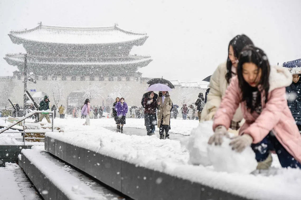 Visitors walk in front of the Gyeongbokgung Palace amid heavy snowfall in central Seoul on Nov 27, 2024. 