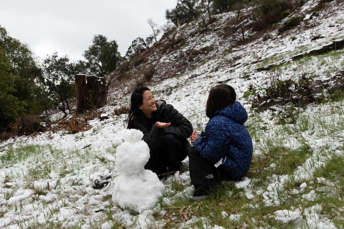 Christina Young and her daughter Jules make a snowman as snow falls over the hills in California on Feb 24, 2023.