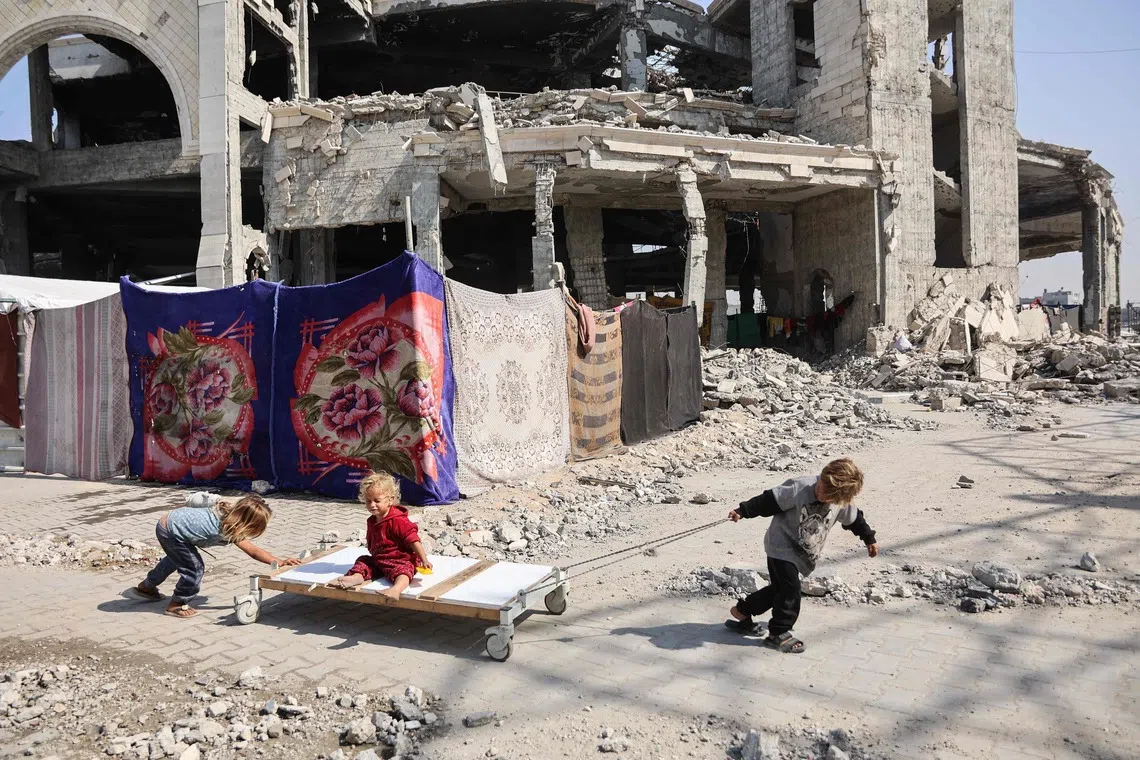 Displaced Palestinian children playing outside the damaged Imam al Shafii Mosque, where their families have taken shelter, in the Zeitoun neighbourhood of Gaza City on Oct 23, 2025. 