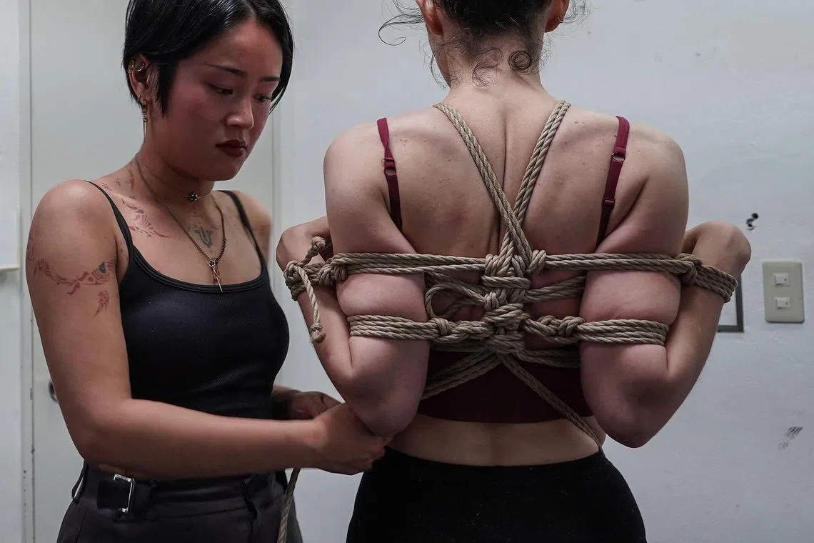 French student Sen (left) applies rope on a model during a certification test to become a “shibari” instructor, at Mr Hajime Kinoko’s studio in May. 
