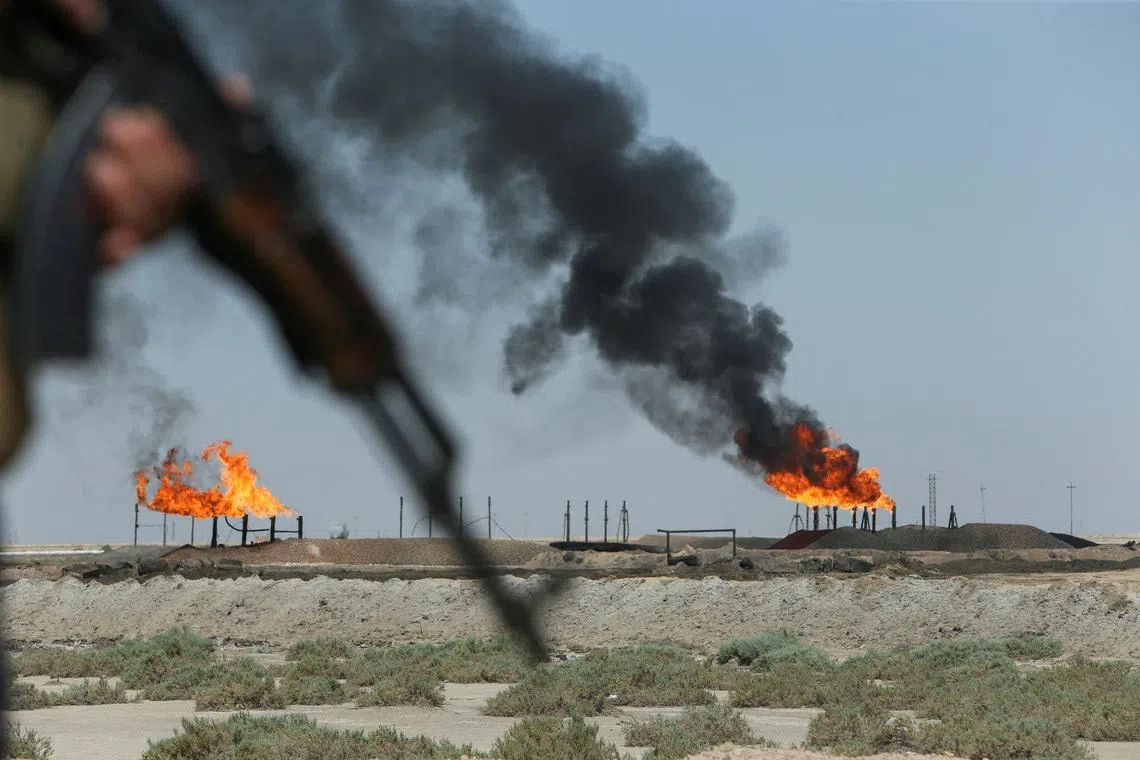 Gas flares burning at the Rumaila oil field as an Iraqi Energy Police officer secures the area in Basra, Iraq, on June 8, 2026. 
