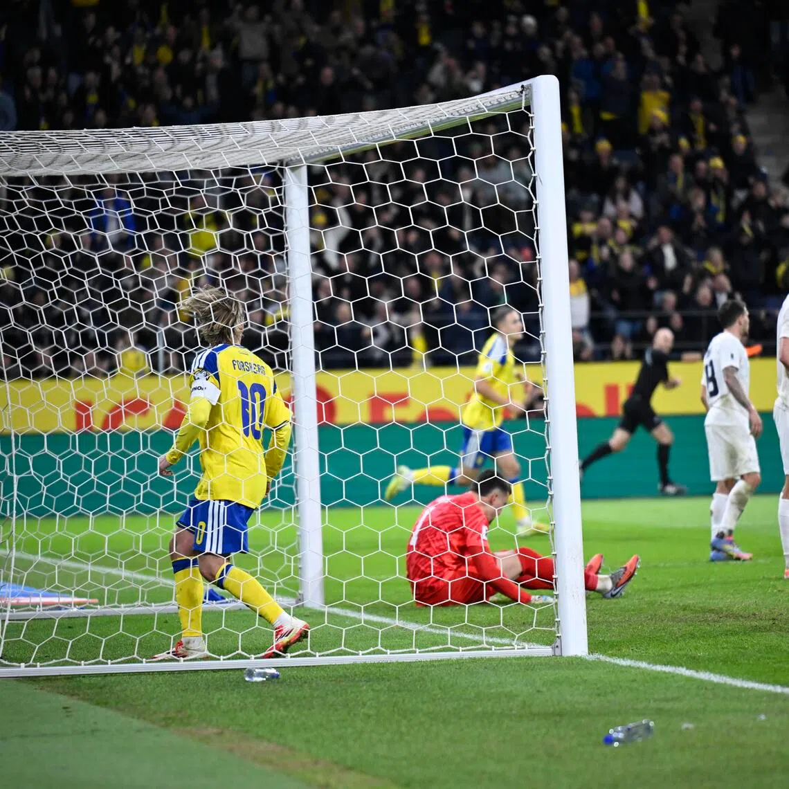 Sweden's Emil Forsberg retrieves the ball in the Slovenia goal behind goalkeeper Igor Vekic, after Gustav Lundgren equalised for a 1-1 draw in their World Cup qualifying match in Stockholm on Nov 18, 2025.