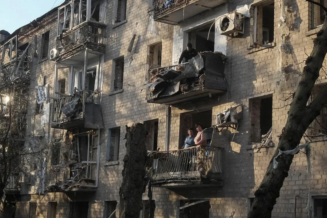 Residents stand at a balcony of an apartment building damaged during  a Russian missile strike, amid Russia's attack on Ukraine, in Dnipro, Ukraine. REUTERS/Stringer