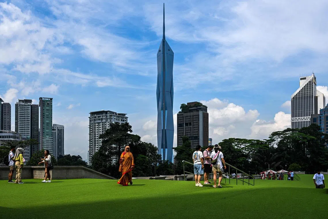 Tourists walk on the compound of the KL Tower in front of the second tallest building in the world, Warisan Merdeka Tower (KL118) (C) in Kuala Lumpur on May 15, 2024. (Photo by Mohd RASFAN / AFP)