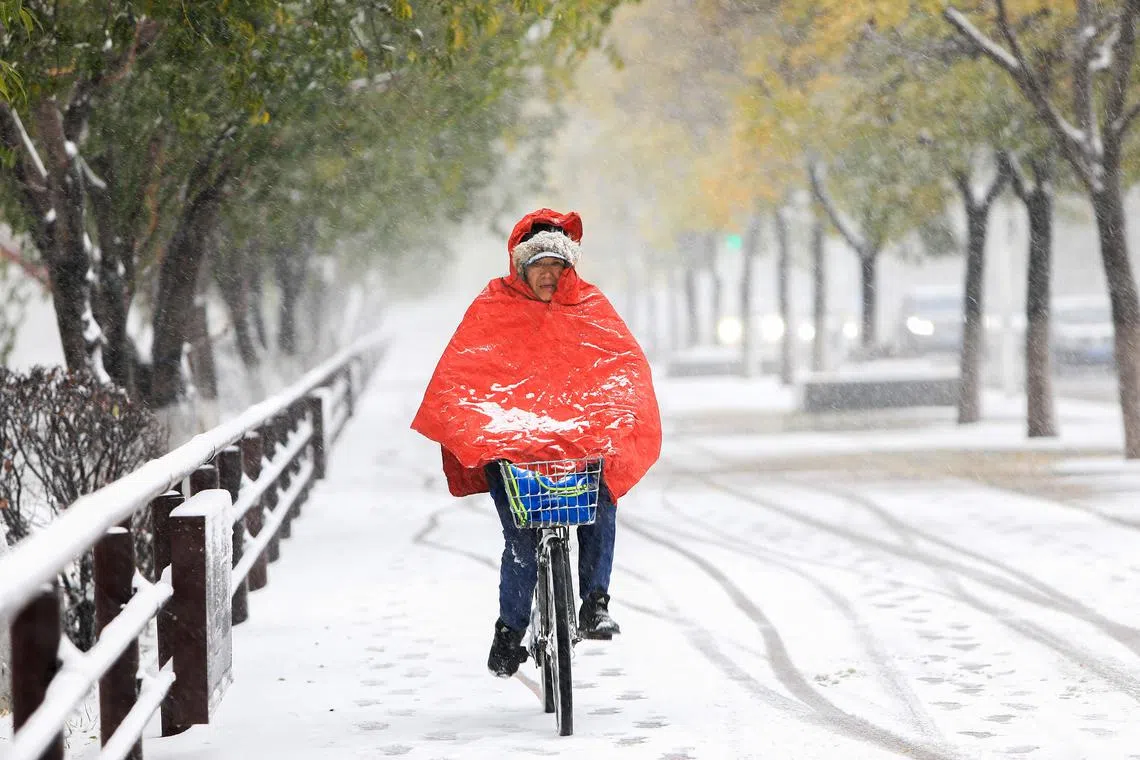 This photo taken on November 6, 2023 shows a person riding bicycle as it snows in Shenyang, in China's northeastern Liaoning province. (Photo by AFP) / China OUT
