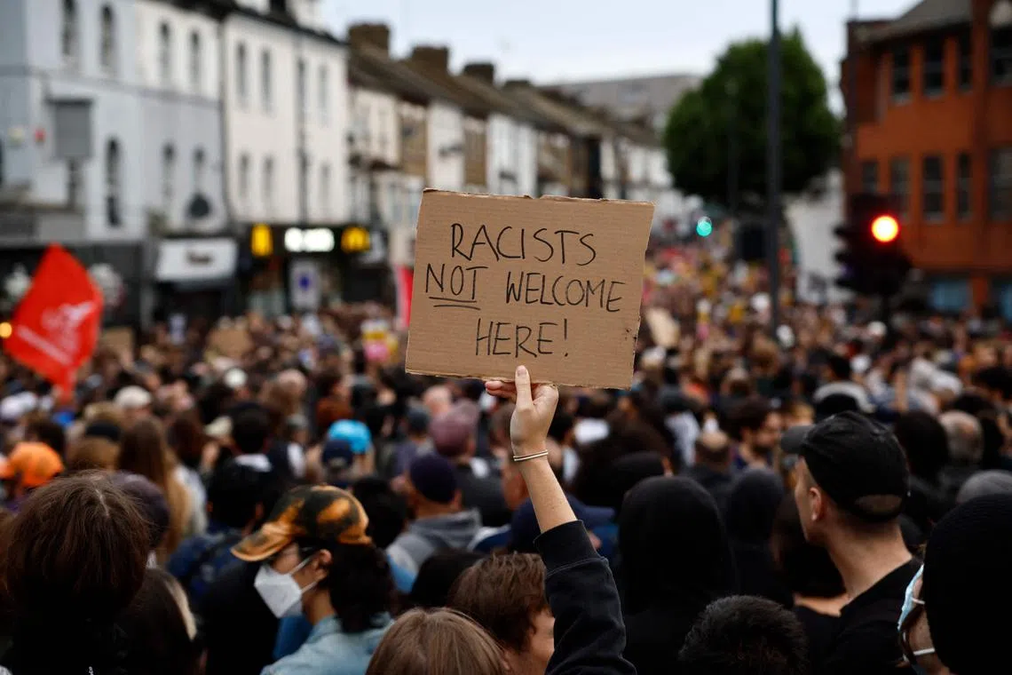 A protester holds a placard reading "Racists not welcome here" during a counter demonstration against an anti-immigration protest called by far-right activists in the Walthamstow suburb of London on Aug 7. 
