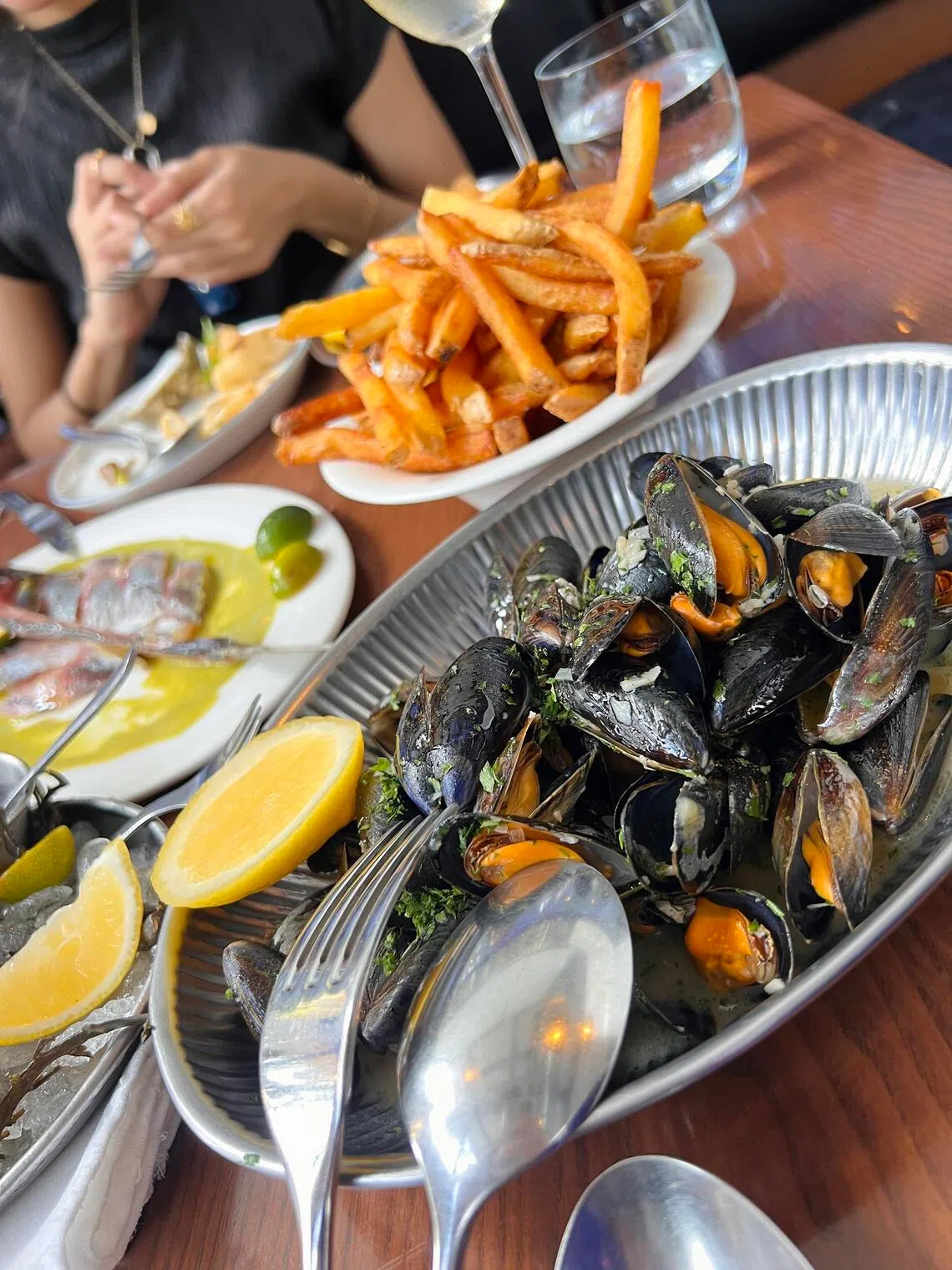 A pot of mariniere mussels bursting with white wine and butter sauce, served with pommes frites at Scuba BKK.