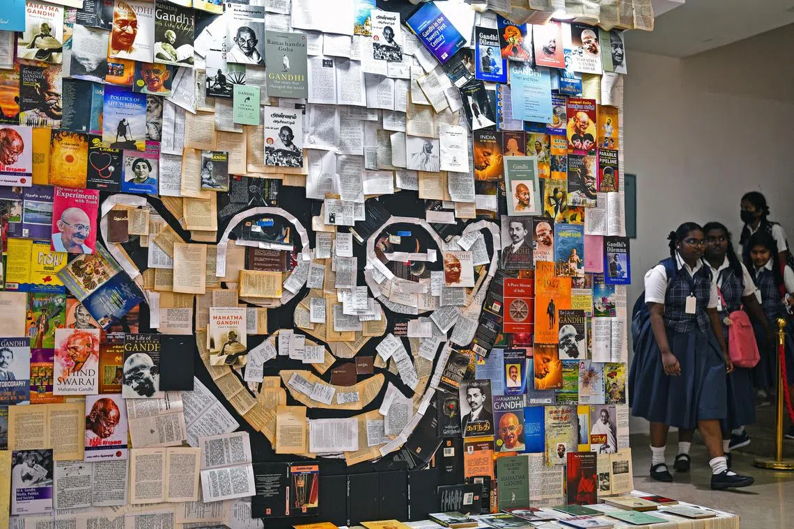 School students walk next to a paper mosaic depicting Mohandas Karamchand Gandhi on the occasion of Martyr's Day, marking his 75th death anniversary at Egmore Museum in Chennai, India.