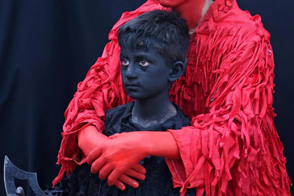 A boy has his body painted in black to portray a demon as he prepares to join an annual religious performance of Taziyeh in the Iranian city of Nushabad on July 26, 2023, during the Muslim month of Muharram in the lead-up to Ashura, a 10-day period commemorating the seventh century killing of Prophet Mohammed's grandson Imam Hussein. 